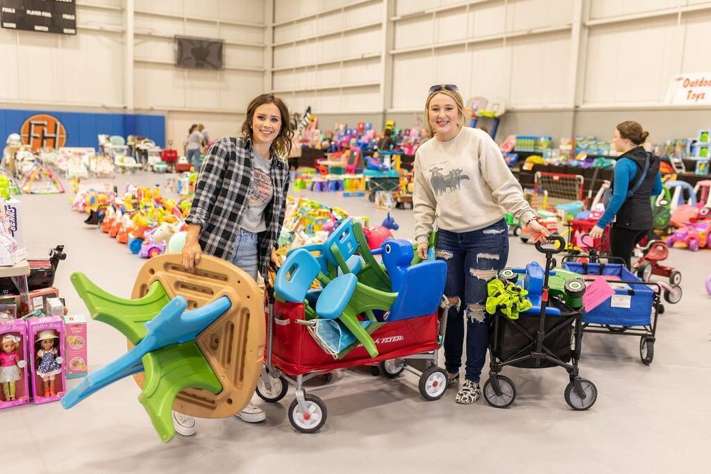 Two moms shopping in the toy gym with wagons full of toys.