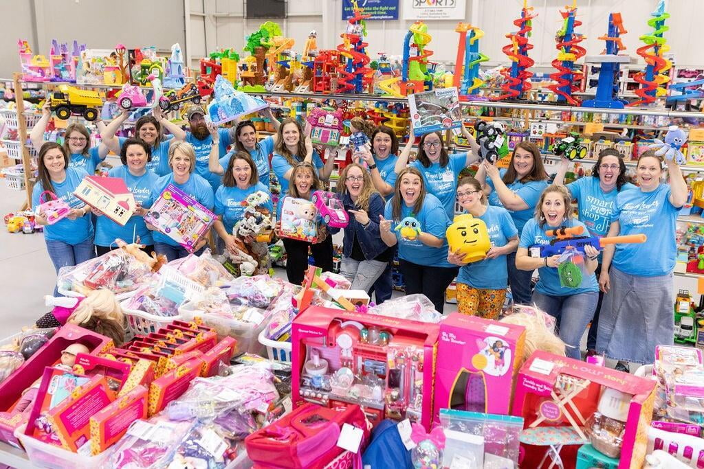 JBF Springfield team members in front of toy shelves holding up toys and smiling.